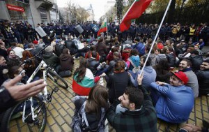 Protesters sit in front of the police as they block a street near the parliament in central Sofia