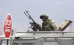 An armed man, believed to be Russian serviceman, is seen in an armoured military vehicle outside a Ukrainian military unit in the village of Perevalnoye outside Simferopol