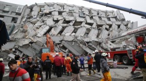 Rescue workers search a collapsed building from an early morning earthquake in Tainan, Taiwan, Saturday, Feb. 6, 2016. A powerful, shallow earthquake struck southern Taiwan before dawn Saturday. (AP Photo/Wally Santana)
